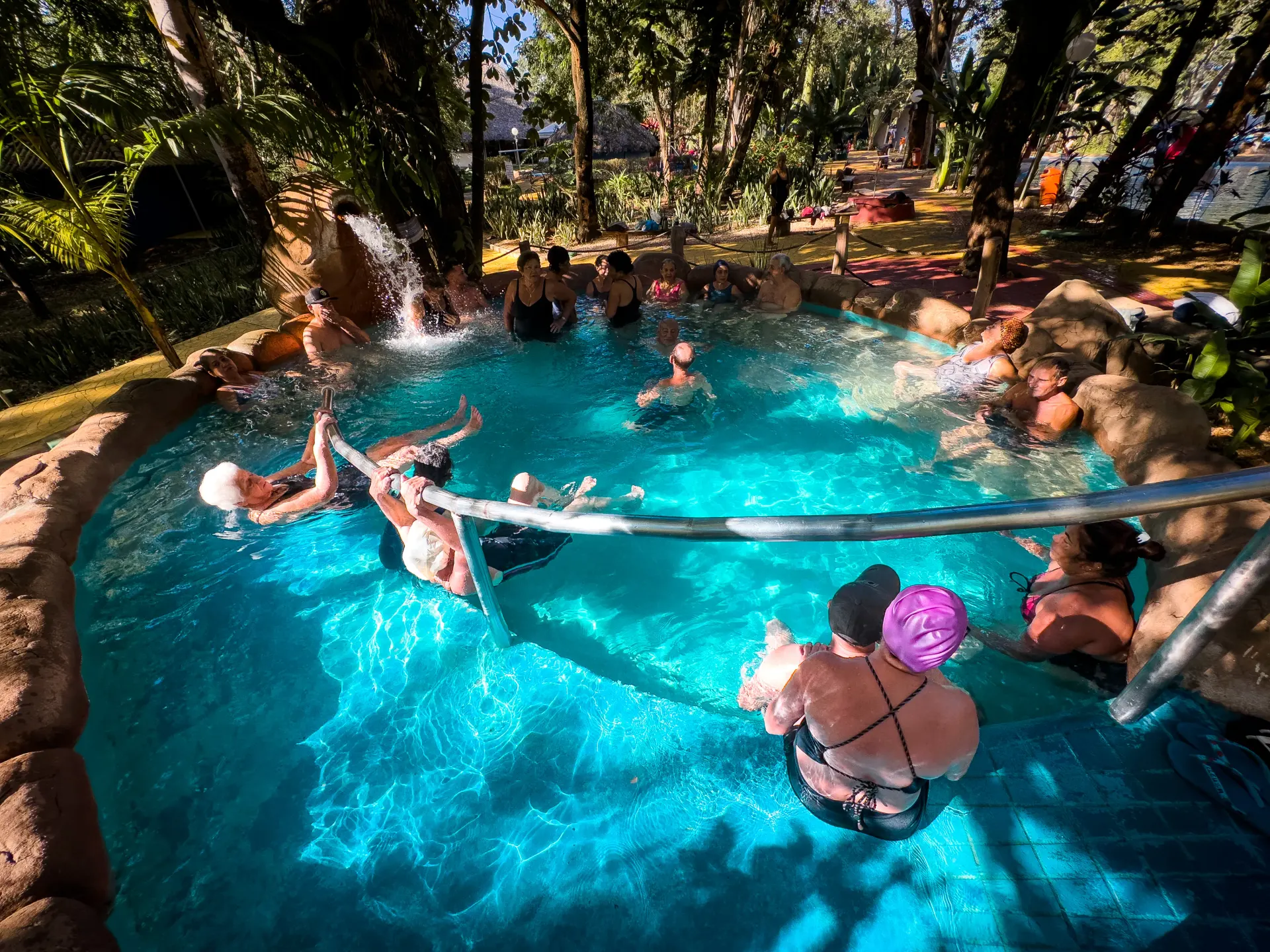 Piscina mais quente do Parque das Águas Quentes, com vapor saindo da água e banhistas sentados na borda