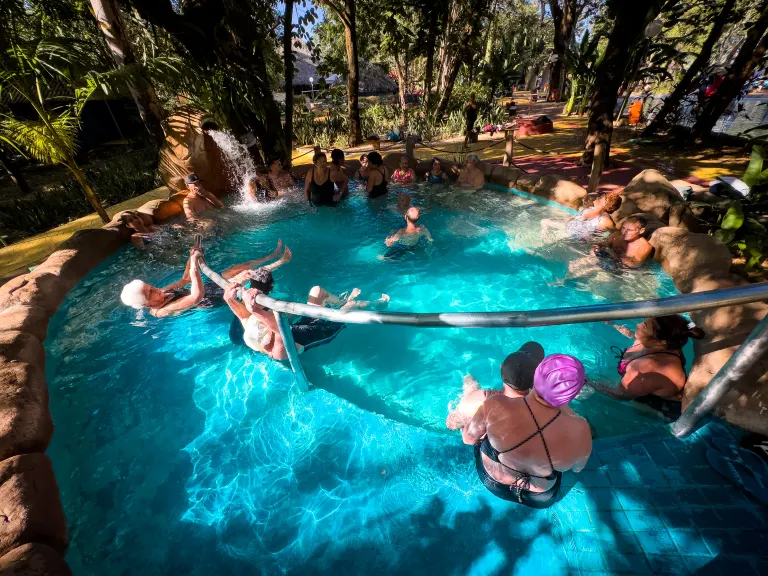 Piscina mais quente do Parque das Águas Quentes, com vapor saindo da água e banhistas sentados na borda