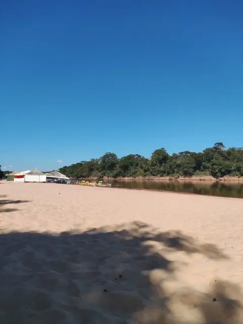 areia da praia do bosque, rio e um bar feito de tendas