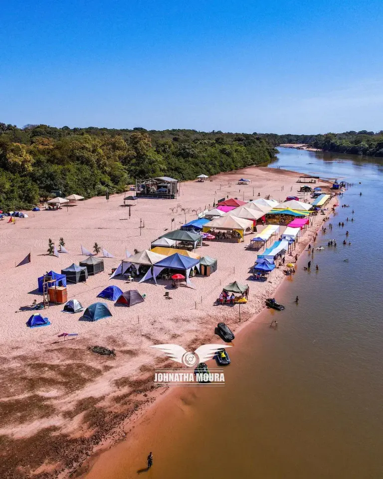 barracas coloridas de camping na areia da Praia da Arara, vistas do alto, com o rio ao lado