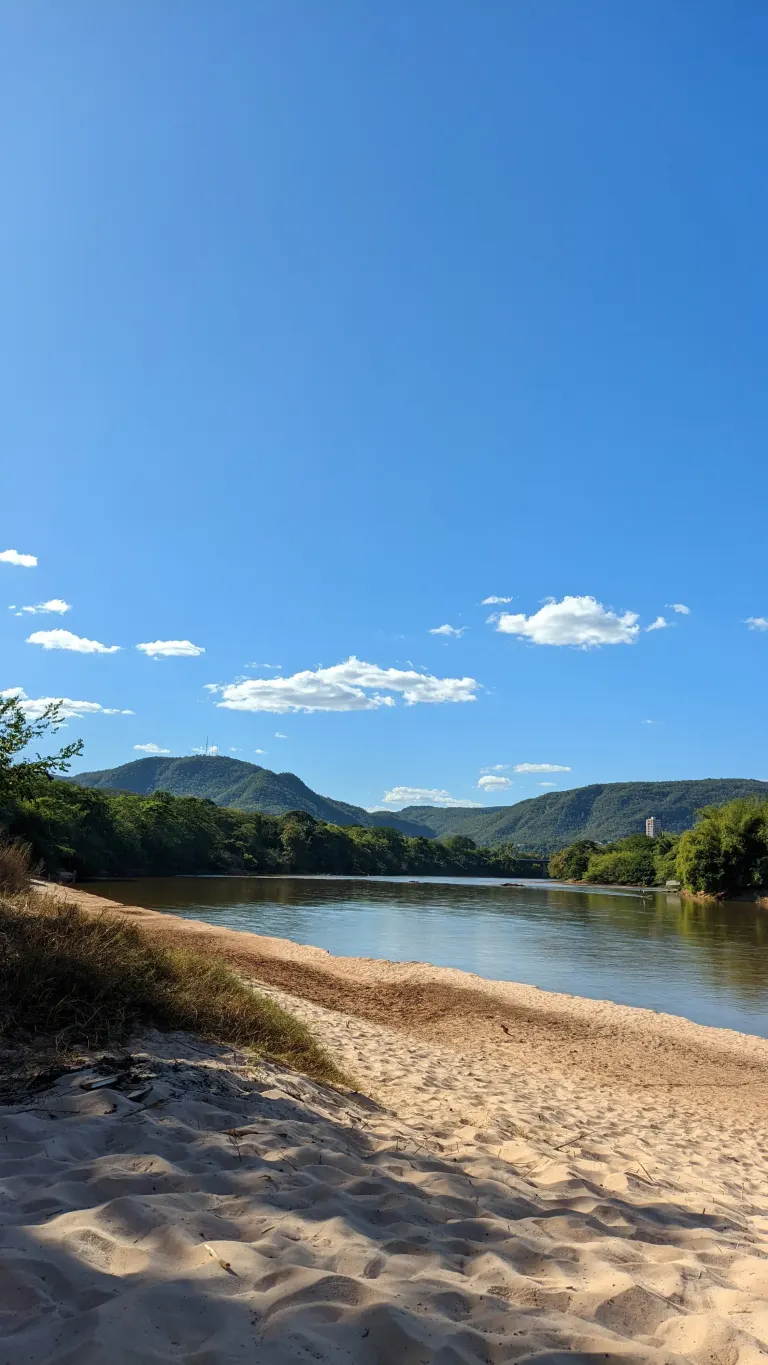 foto que mostra uma faixa grande de area, o rio, e de fundo a serra do parque estadual Serra Azul.