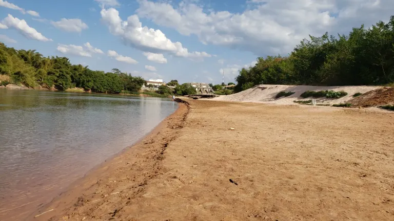 na metade esqueda da foto tem o rio e na metade direta da foto tem a faixa de areia da praia.