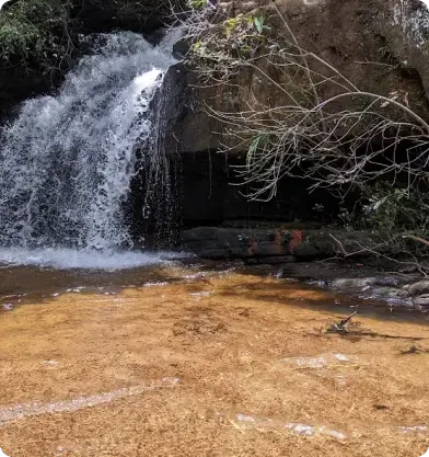 Cachoeira com pequena queda d'água e grande volume, parte da Trilha das Cachoeiras.