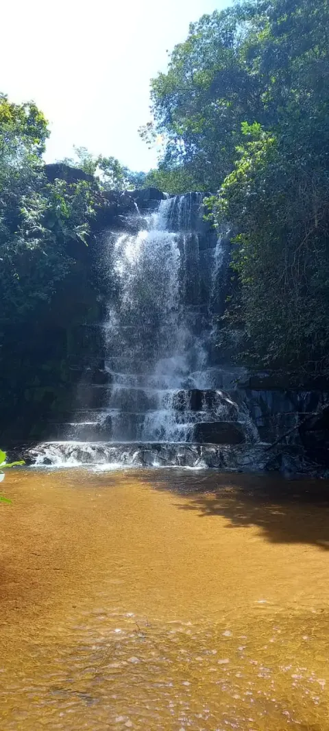 uma das cachoeiras da trilha com queda d'água de aproximadamente 5 metros e formações rochosas em degraus naturais, mas sem pessoas.